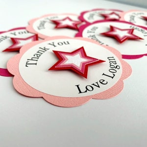 May include: Pink and white scalloped circle thank you tags with a red, pink, and white layered star. The text on the tag reads "Thank You Love Logan".
