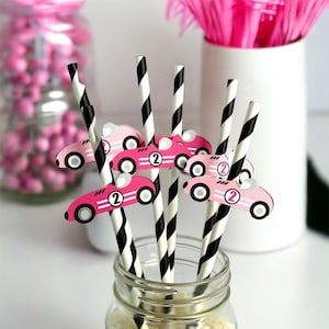 May include: Black and white striped paper straws with pink race car cutouts. The race cars have the number "2" on them.
