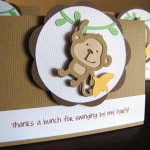 May include: A brown thank you card with a white scalloped circle featuring a cartoon monkey hanging from a green vine. The text "thanks a bunch for swinging by my party!" is printed on the card.
