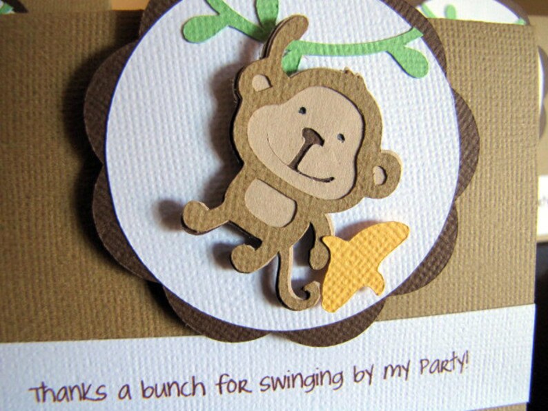 May include: A brown card with a white circle in the center. The circle has a brown monkey with a yellow butterfly on a green vine. The text "Thanks a bunch for swinging by my party!" is at the bottom of the card.