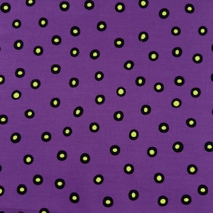 May include: A close-up of a purple fabric with a repeating pattern of black circles with yellow-green centers. The circles are randomly spaced across the fabric, creating a playful and eye-catching design.