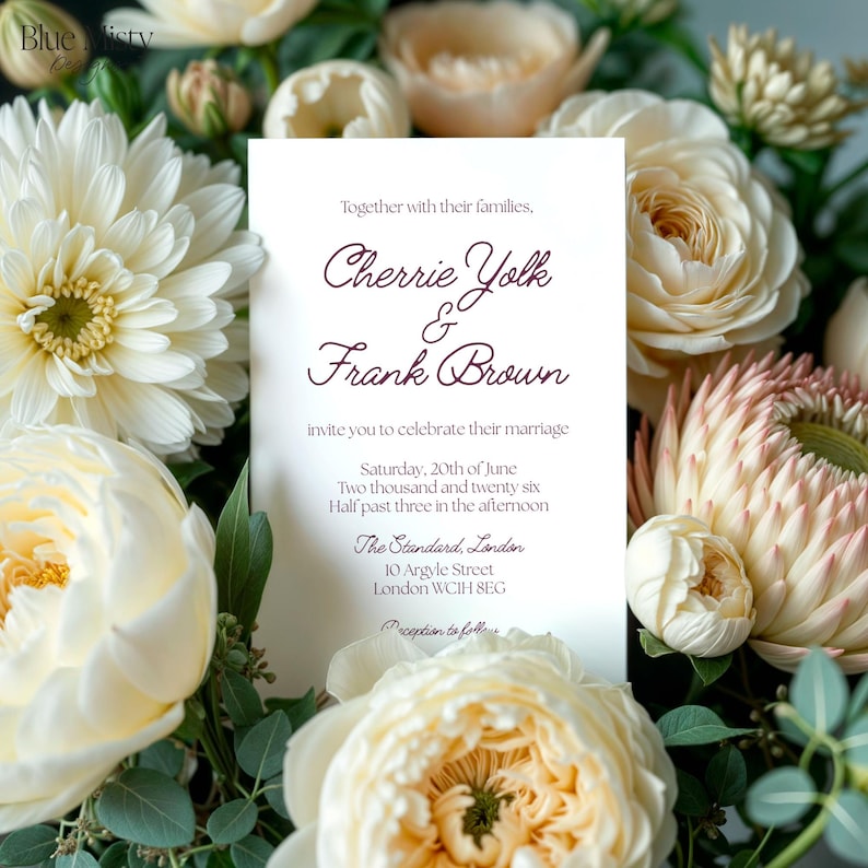 May include: A wedding invitation featuring the names "Cherrie Yolk & Frank Brown" in a stylish font. The invitation is set against a backdrop of cream and white flowers. The text includes the date, time, and venue in London.