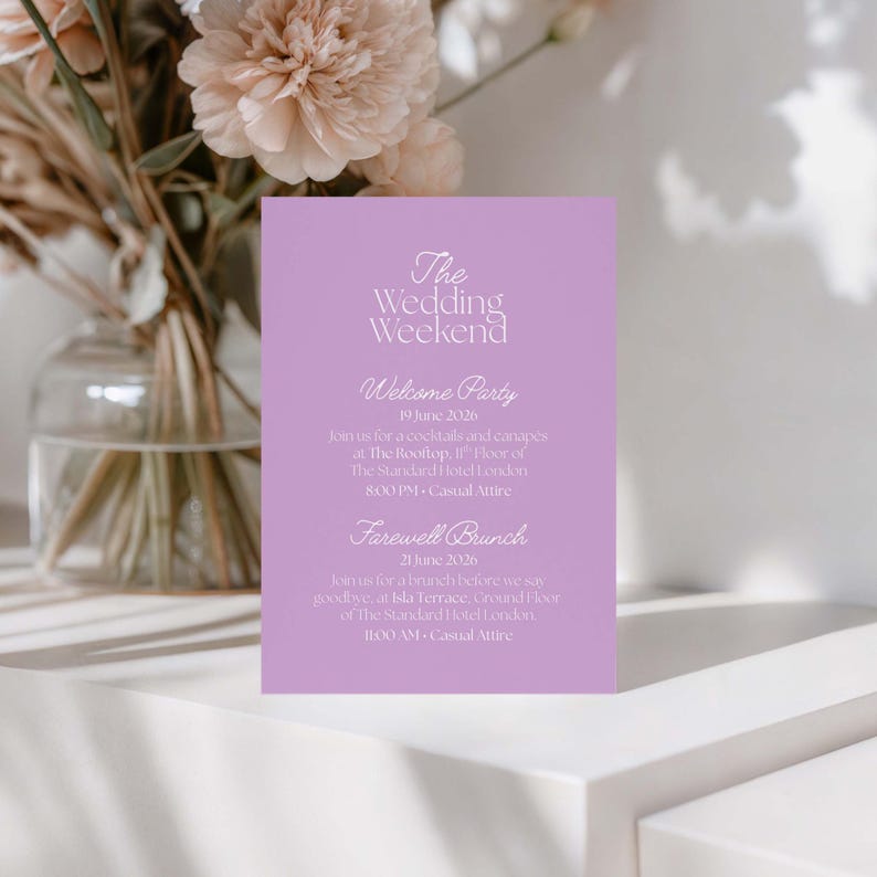 May include: A lilac wedding invitation card with the text "The Wedding Weekend." Details include a welcome party and farewell brunch with dates, times, and locations. A vase of flowers is in the background.