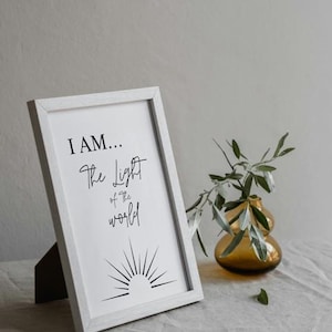 May include: White framed print with the text "I AM... The Light of the World" and a stylized sun graphic.