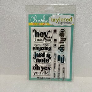 May include: A clear stamp set with various phrases like "hey," "I miss you," and "you are amazing." The set includes the text "Clearly Crafty Collection" and "taylored expressions" on the packaging.