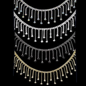 May include: Four strands of fringe trim featuring metallic settings and clear or colored rhinestones. Each strand consists of a horizontal chain with vertical dangling segments of varying lengths, each ending in a single round rhinestone.