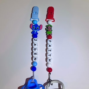 Puede incluir: Dos clips para chupete de bebé. Uno es azul con un personaje de Stitch, el otro es rojo con un personaje de Lilo. Cada clip tiene un nombre escrito con cuentas de letras blancas: JADEN y FAITH. Los clips están sujetos a una botella azul y un anillo gris.