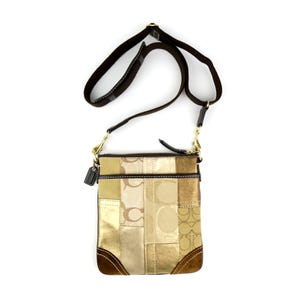May include: A rectangular crossbody bag with a patchwork design in shades of gold, tan, and brown. The bag features a brown strap, gold-tone hardware, and a small leather tag. The bottom corners are a darker brown.