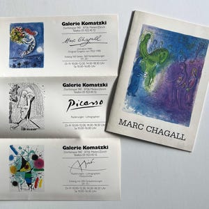 May include: A collection of art gallery promotional materials featuring artwork by Marc Chagall, Picasso, and Miró. The materials include a booklet with a Chagall painting and business cards with artist signatures and contact information.