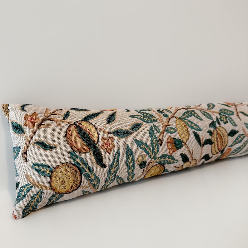 Peut inclure: Un butoir de porte rectangulaire et long, avec un fond beige et un motif r&eacute;p&eacute;t&eacute; de fruits, de feuilles et de fleurs dans des tons de vert, jaune et marron. Le butoir de porte est en tissu tiss&eacute;.