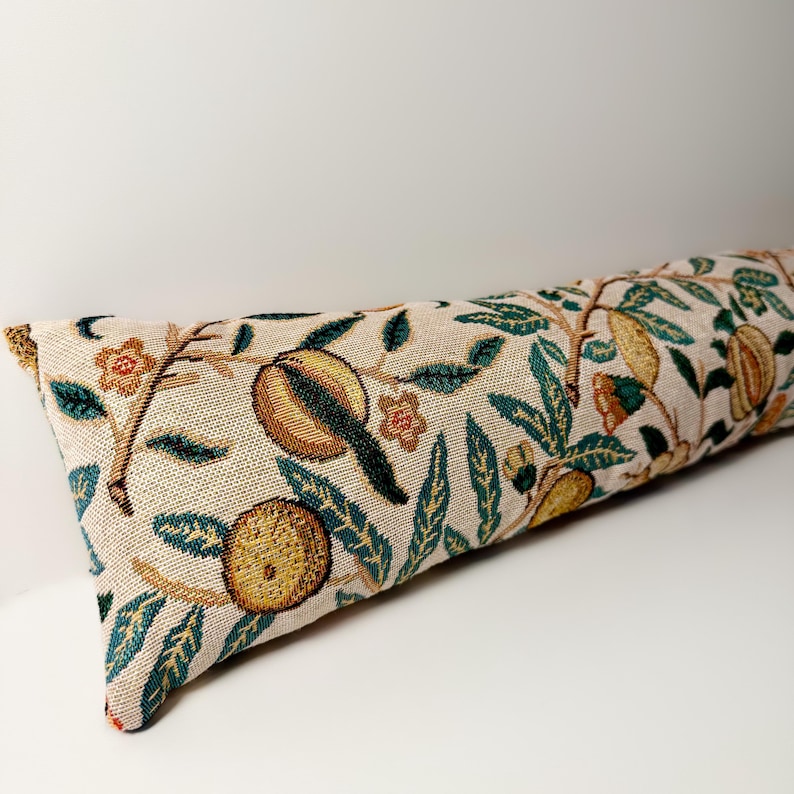 Peut inclure: Un long coussin rectangulaire avec un fond beige et un motif floral d&eacute;taill&eacute;. Le motif comprend des fruits et des feuilles bruns, jaunes et verts. Le coussin est probablement fait d'un tissu tiss&eacute;.