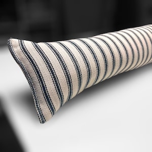 May include: A long, rectangular pillow with a white and black striped pattern. The pillow is made of a soft, textured fabric.