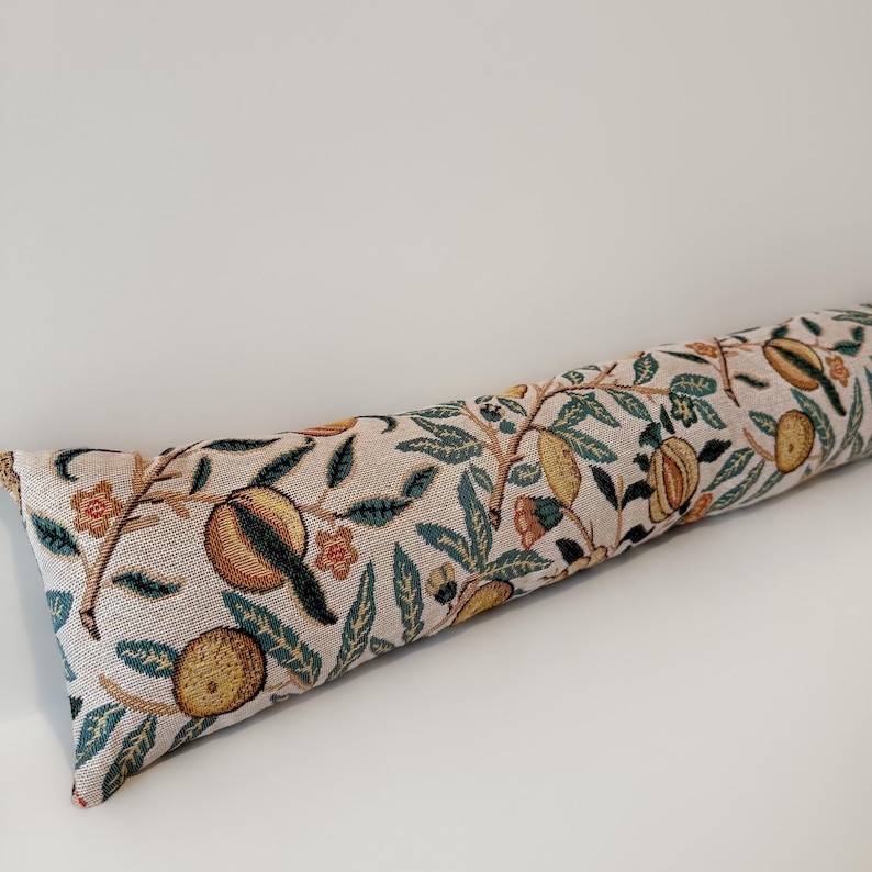 Peut inclure: Un butoir de porte long et cylindrique avec un fond beige et un motif r&eacute;p&eacute;t&eacute; d'oranges, de feuilles et de fleurs dans des tons de jaune, vert et orange. Le butoir de porte mesure environ 61 cm de long.