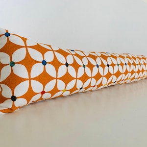 Può includere: Un fermaporta lungo, arancione e bianco con un motivo floreale. I fiori sono bianchi con centri colorati.