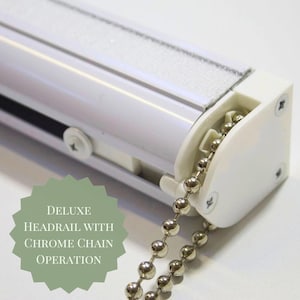 May include: A white deluxe headrail with chrome chain operation. The headrail has a white finish with a silver chain and a white plastic end piece. The text "DELUXE HEADRAIL WITH CHROME CHAIN OPERATION" is visible.