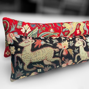 May include: Two decorative throw pillows with a tapestry-like design. The top pillow is red with a yellow and green animal, while the bottom pillow is black with a gold and green animal.