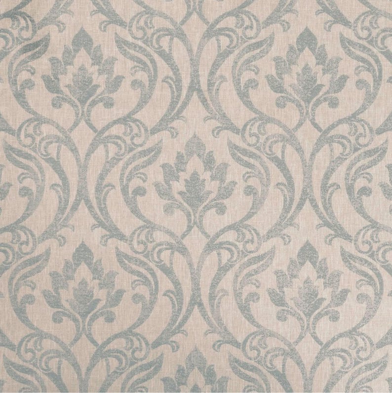 May include: A repeating pattern featuring floral and scroll motifs in a muted blue-grey hue set against a cream backdrop. The design is symmetrical, with each floral element mirrored. The overall aesthetic is one of classic elegance, suitable for various applications.