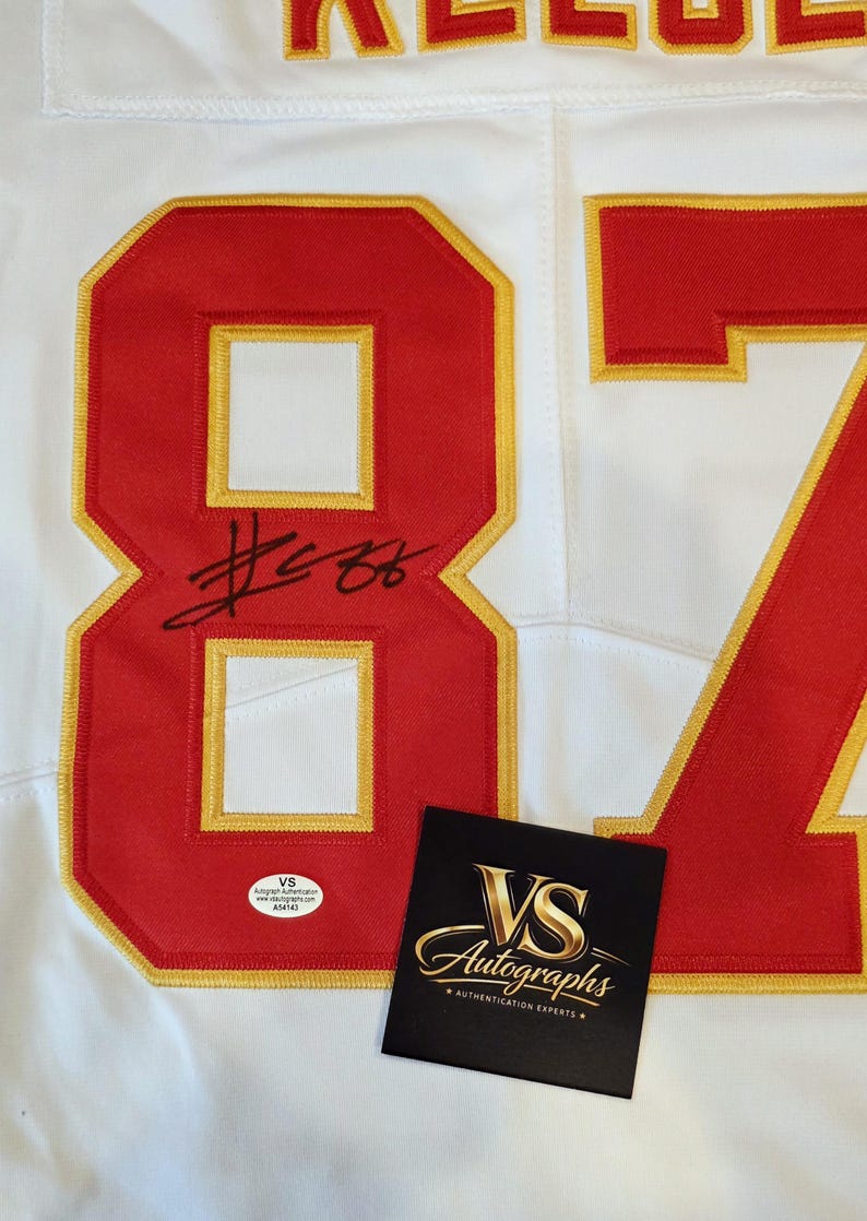 May include: White jersey with red and gold accents, featuring the number 87. The jersey has an autograph and a VS Autographs authentication sticker and card.