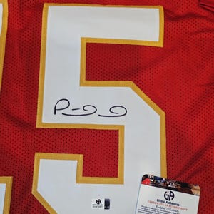 May include: Red and white football jersey with the number 5 in white with gold trim. The jersey has a signature on the number 5. A Global Authentics certificate of authenticity is attached.
