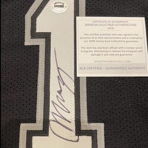 May include: Black jersey with a large white number 1 outlined in gray. The jersey has a certificate of authenticity from American Collectibles Authentication (ACA) and a tamper-proof hologram.