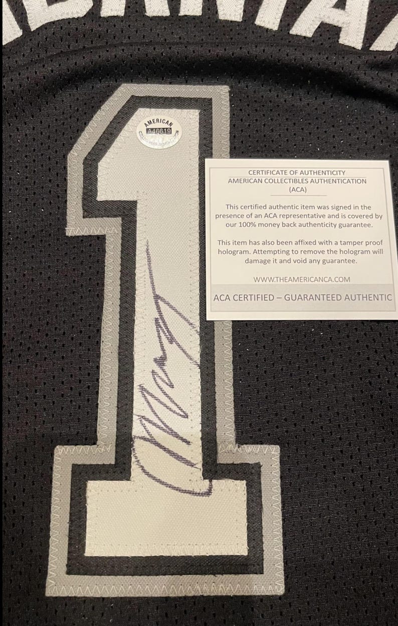 May include: Black jersey with a large white number 1 outlined in gray. The jersey has a certificate of authenticity from American Collectibles Authentication (ACA) and a tamper-proof hologram.