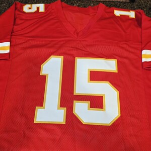 May include: Red football jersey with white and yellow accents. The jersey features the number 15 in large white block letters with a yellow outline on the front. The sleeves have white and yellow stripes.