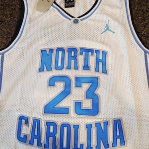 May include: White mesh basketball jersey with blue accents. Features the words "NORTH CAROLINA" and the number "23" in blue. Includes a tag with the Jordan logo.