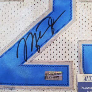 May include: Close-up of a white mesh jersey with blue accents and a black signature. The jersey has a blue number 2, a blue and silver trim, and a small authentication sticker.