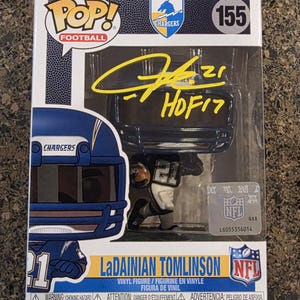 May include: A Funko Pop Football vinyl figure of LaDainian Tomlinson, number 155, in a Chargers uniform. The box features a yellow autograph with the number 21 and HOF17, an NFL hologram sticker, and the text LaDainian Tomlinson and Chargers.