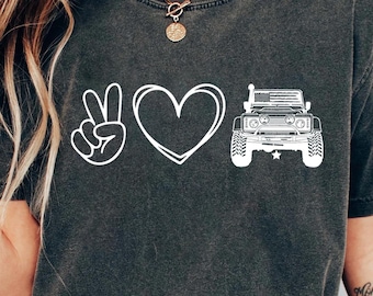 May include: A dark gray t-shirt with a white peace sign, heart, and a jeep graphic. The text "Peace Love Jeep" is not visible in the image.