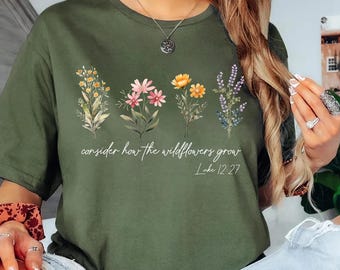 May include: Military green t-shirt with a floral design and the text "consider how the wildflowers grow" and "Luke 12:27". The shirt features a crew neck and short sleeves.