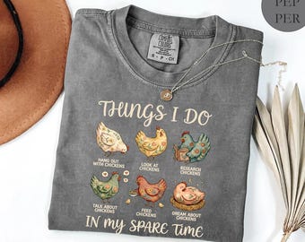May include: A grey Comfort Colors t-shirt featuring the text "Things I Do" and chicken illustrations. The shirt also says "Hang out with chickens", "Look at chickens", "Research chickens", "Talk about chickens", "Feed chickens", and "Dream about chickens" in my spare time.
