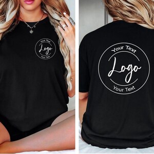 Puede incluir: Una camiseta negra de manga corta con un gr&aacute;fico circular blanco en la parte delantera izquierda del pecho y una versi&oacute;n m&aacute;s grande del mismo gr&aacute;fico en la espalda. El gr&aacute;fico contiene el texto Your Text, Logo y Your Text en un marco circular.