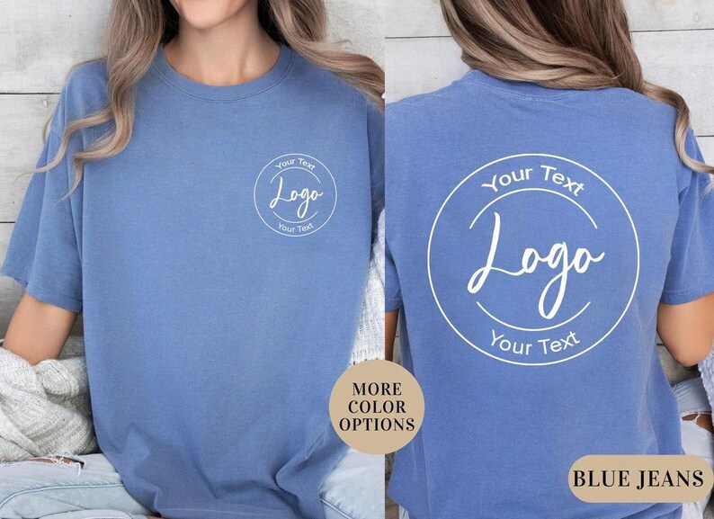 Puede incluir: Una camiseta azul de manga corta con un gr&aacute;fico circular blanco en el pecho izquierdo y una versi&oacute;n m&aacute;s grande del mismo gr&aacute;fico en la espalda. El gr&aacute;fico contiene el texto Your Text, Logo y Your Text dentro de un marco circular blanco.