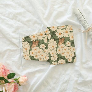 May include: A clear phone case and a matching phone case cover featuring a floral pattern with cream-colored flowers, green leaves, and a squirrel peeking out. The design is set against a dark green background.