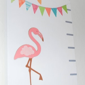 May include: A white wall-mounted growth chart featuring a pink flamingo, colorful bunting, and decorative flowers. The chart includes a height scale with markings and the number 5. The flamingo is standing on a blue shape.