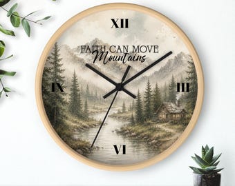 May include: A round wall clock with a light wood frame. The clock face features a landscape painting of a river, mountains, and a cabin. The text "FAITH CAN MOVE Mountains" is printed on the clock face.
