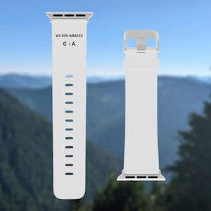 May include: Two white watch straps. One strap has the text "VII-XXII-MMXXV" and "C + A". The other strap has a silver buckle. The straps are set against a blurred mountain backdrop.
