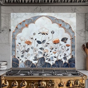 May include: A kitchen with a gold-colored stove and gray cabinets. A decorative backsplash features a floral design with white, orange, and blue flowers within an arched frame. The kitchen has a marble countertop and a stainless steel range hood.