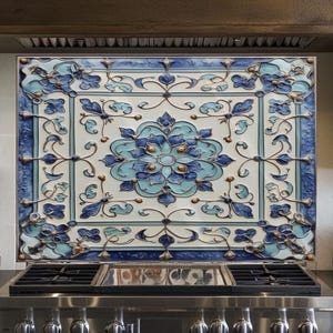 May include: A decorative kitchen backsplash with a floral design in shades of blue and white. The backsplash is installed above a stainless steel gas range. The design features a central flower motif surrounded by ornate patterns and borders.