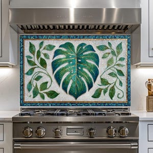 May include: A decorative kitchen backsplash featuring a mosaic design with a large, teal Monstera leaf and green vines. The leaf has gold accents, and the border is teal and gold. The backsplash is installed above a stainless steel range.