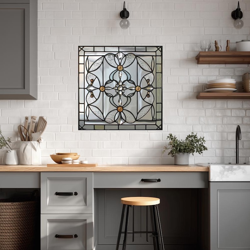 May include: A decorative stained glass window with a black metal frame. The window features a floral design with clear, gold, and amber-colored glass. The window is mounted in a white brick wall above a kitchen countertop.