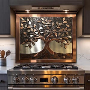 May include: A copper-framed metal art piece featuring a tree design, installed above a stainless steel gas range. The tree has silver and copper-colored leaves and trunk, set against a textured dark background. The kitchen decor adds a touch of nature.