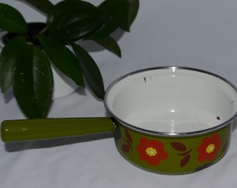 May include: Green enamel saucepan with a white interior and a floral design featuring orange and brown flowers. The saucepan has a green handle.