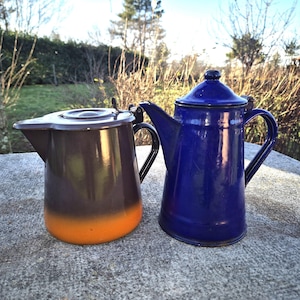 Könnte beinhalten: Zwei emaillierte Kaffeekannen, eine ist braun mit orangefarbenem Boden und die andere ist blau. Beide haben einen Griff und einen Ausguss.