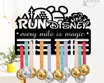 May include: Black metal Run Disney medal holder with the text "every mile is magic." The holder features a Mickey Mouse silhouette and holds several medals with colorful ribbons. The medals are gold and silver.