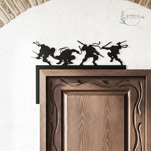 May include: Black metal silhouette of four ninja turtles in action poses, mounted above a wooden door. The figures are detailed with weapons and bandanas, creating a dynamic and decorative accent for a room.