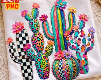 May include: A white t-shirt featuring a vibrant, textured graphic of multiple cacti. The cacti display colourful patterns including black and white checkers, neon leopard spots, and vertical stripes, all topped with bright pink, yellow, and purple flowers.