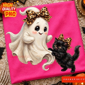 May include: A bright pink t-shirt featuring a graphic of a white ghost and a fluffy black kitten. Both the ghost and the kitten are wearing matching leopard print bows. The ghost has large black eyes and rosy cheeks, while the kitten is shown in a playful pose.