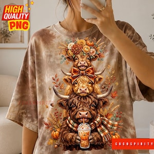 May include: A brown tie-dye t-shirt featuring a graphic of three stacked Highland cows. The top cow wears a floral crown, the middle cow has a bow, and the bottom cow wears a plaid scarf while holding a pumpkin spice latte with a pumpkin design.